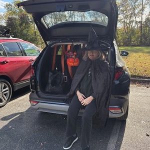 Costumed guest beside a decorated trunk at a previous Trinity Trunk or Treat